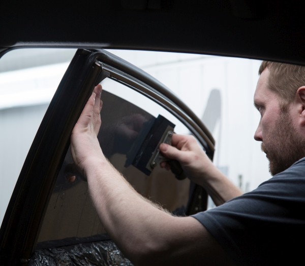 Technician tinting a car window