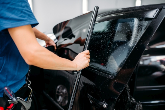 Technician installing car window tint